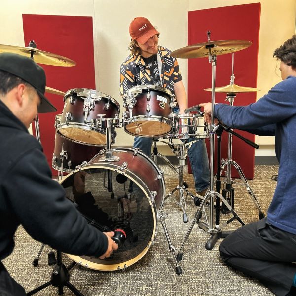 Students setting up drum mics in a recording studio.