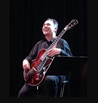 Gino Raugi smiling with his guitar
